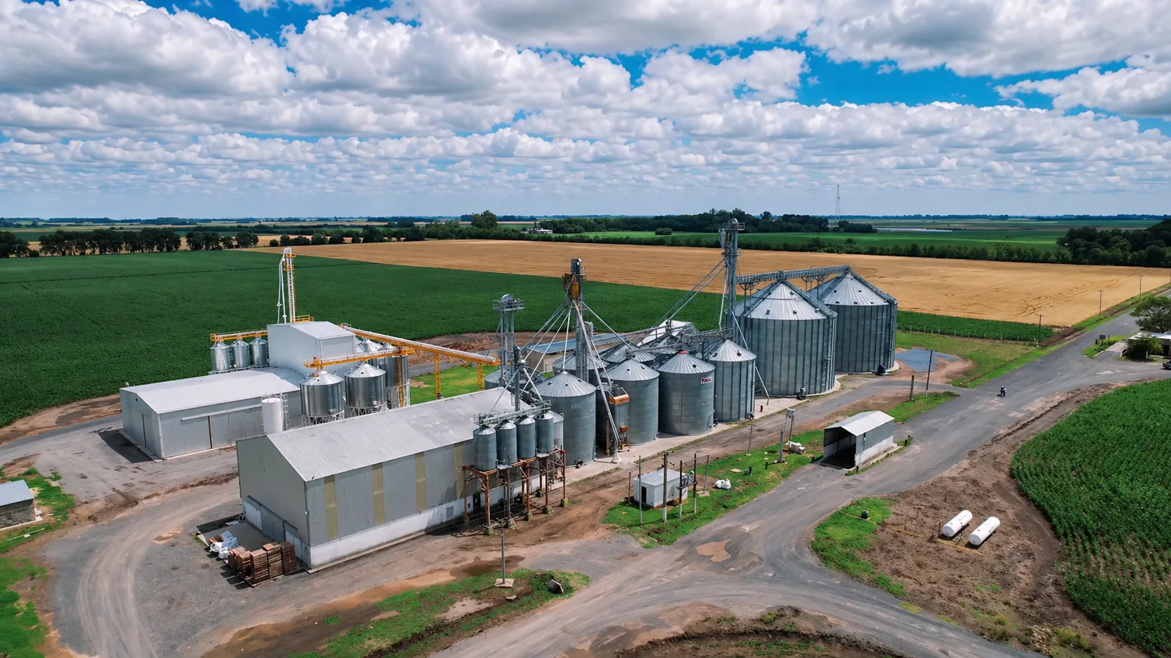 Planta agroindustrial con silos y campos productivos